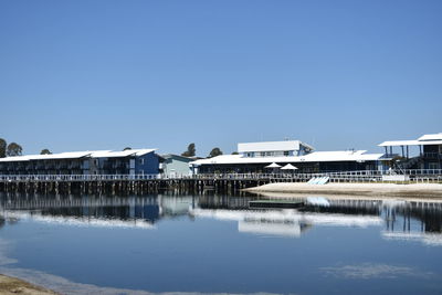 Reflection of built structures in water against clear blue sky