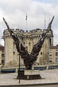 Statue in city against sky