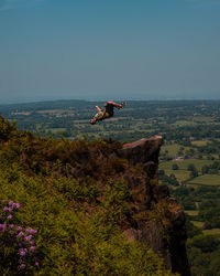 Full length of man jumping at cliff against sky