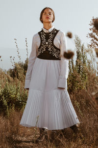 Full length of woman standing on field against sky