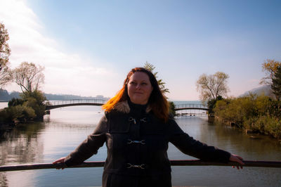 Portrait of woman standing against river against sky