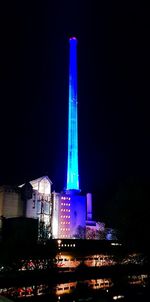 Illuminated buildings against blue sky at night