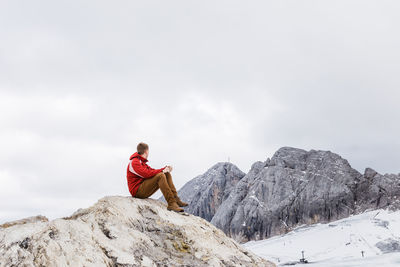 Young millennial man enjoys the views of the alps standing on glacier