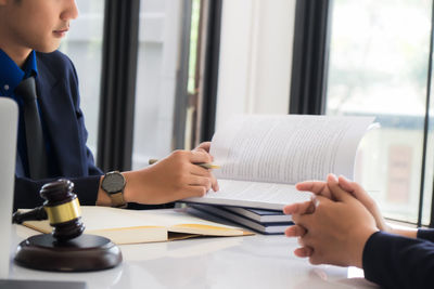 Midsection of man holding book on table