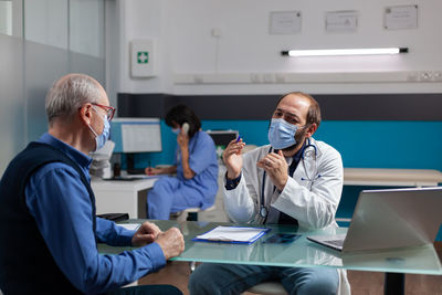 Doctor wearing mask talking with patient