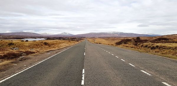 Road leading towards mountains against sky