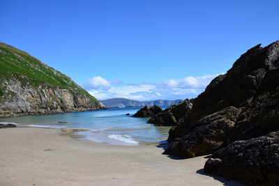 Scenic view of sea and mountains against blue sky