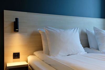 Fragment of bedroom with empty bedside table, turn on reading lamp and socket in modern interior