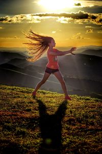 Woman exercising on grass at sunset