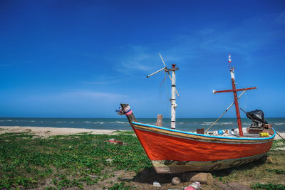 Boat moored on beach against sky