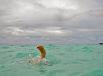 Man surfing in sea against sky