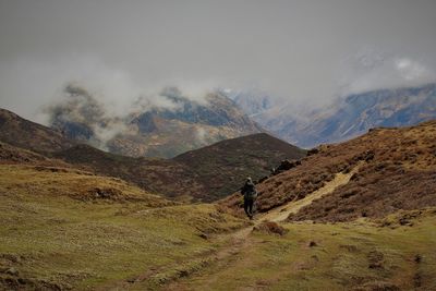 Man walking on mountain against sky