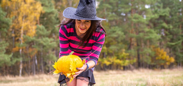 Young witch with pumpkin in the autumn forest. halloween concept