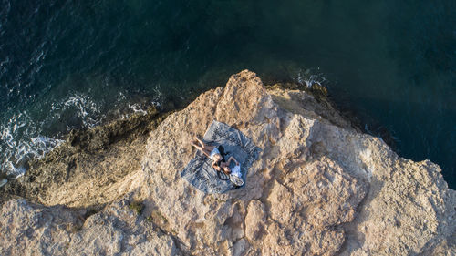 Aerial view of woman relaxing on cliff by sea