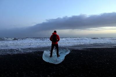 A man standing on glacier ice at the diamond beach in iceland 