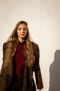 Portrait of a beautiful young woman standing against wall