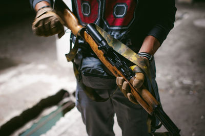 Midsection of man holding rifle