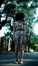 Rear view of woman walking on road against trees