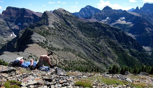 People sitting on rocks against mountain range