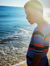 Side view of young man standing at beach