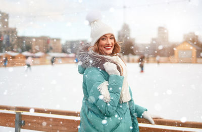 Portrait of smiling young woman wearing knit hat standing outdoors