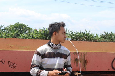 Full length of young man looking away against sky