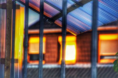 Illuminated building seen through metal fence