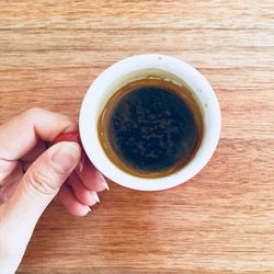 Directly above shot of person holding coffee cup on table