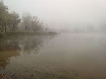 View of calm lake in foggy weather