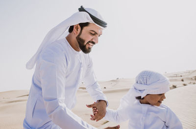 Smiling father and son enjoying while standing in desert