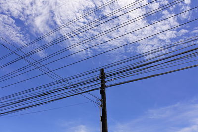 Low angle view of electricity pylon against blue sky