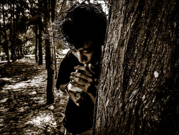 Man standing by tree trunk in forest