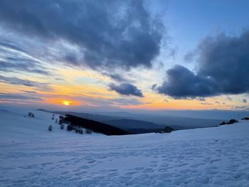 Dramatic sky at sunset over mountains covered in snow