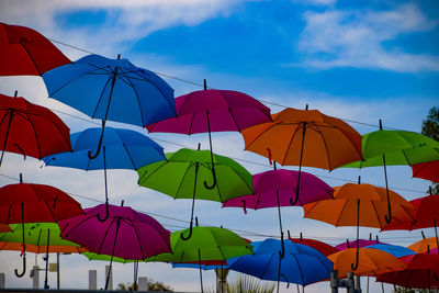 Low angle view of umbrellas hanging against sky