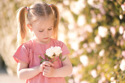 Cute girl holding flower standing outdoors