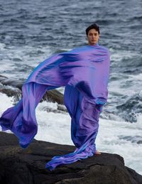 Portrait of woman standing on rock against sea