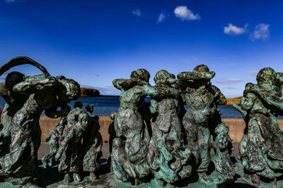 Stack of rocks by sea against blue sky