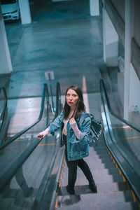 Full length portrait of young woman standing by car