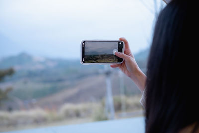 Midsection of woman photographing through smart phone