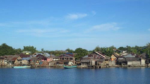 Houses by lake and buildings against sky