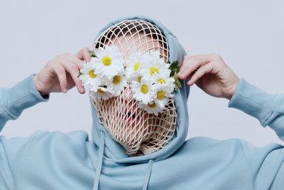 Midsection of woman holding basket against white background