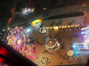 Illuminated ferris wheel seen through car window at night