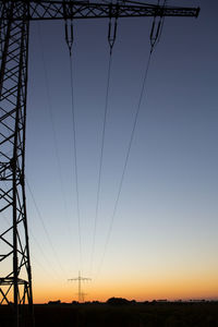 Low angle view of silhouette electricity pylon against sky during sunset