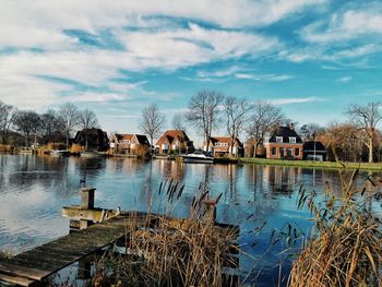 Houses by lake against sky