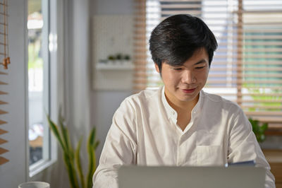 Young man using digital tablet while standing in office