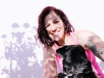 Portrait of smiling woman with dog against clear sky