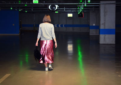 Rear view of woman standing in illuminated corridor