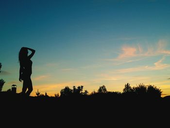 Silhouette man standing by tree against sky during sunset