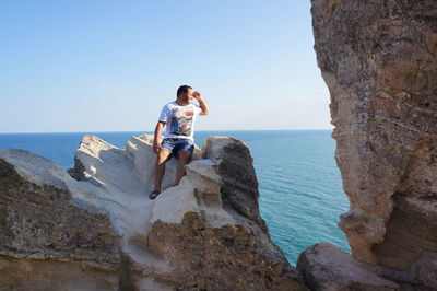 Man sitting on rock against sea