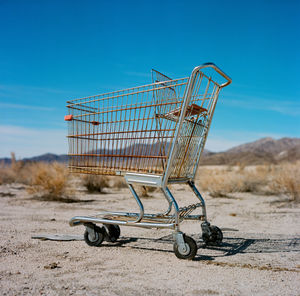 Abandoned shopping cart against blue sky